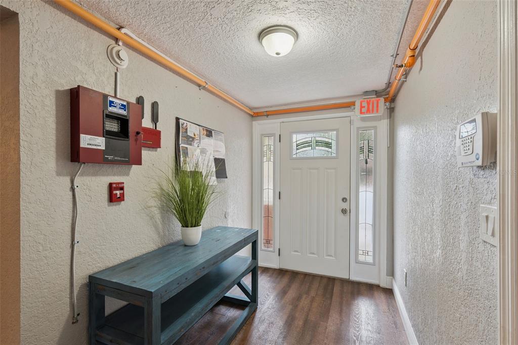 A brightly lit entryway features a blue console table, fire alarm equipment, and a white door — 78 S WINTER PARK DRIVE, CASSELBERRY, FL