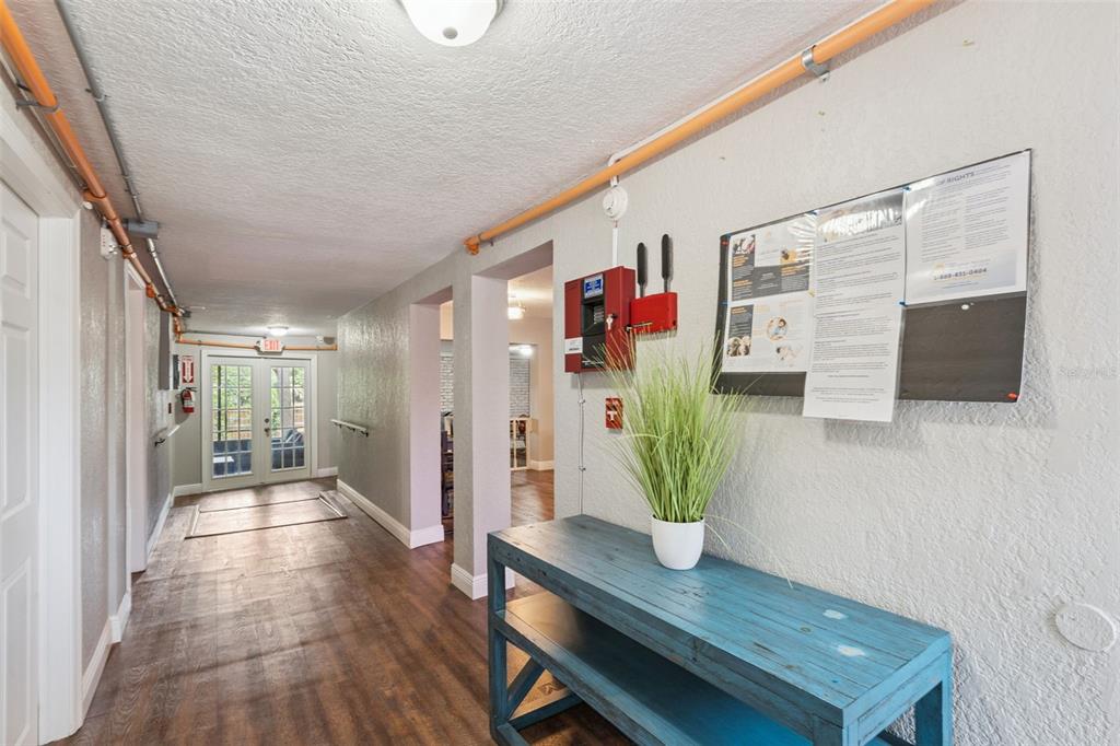 A hallway features wood-look flooring, a blue console table, and a wall-mounted fire alarm panel — 78 S WINTER PARK DRIVE, CASSELBERRY, FL