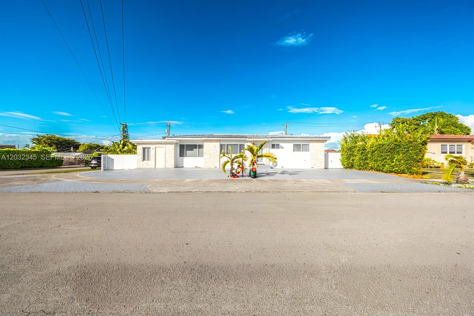 A single-story house with a paved driveway and white exterior sits under a blue sky — 9365 SW 44th St, Miami FL 33165, MIAMI, FL
