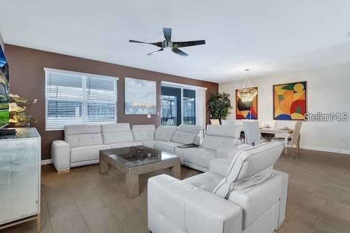 A living room with white leather sectional seating, a glass coffee table, and dining area — 4535 NARRATIVE LANE, KISSIMMEE, FL