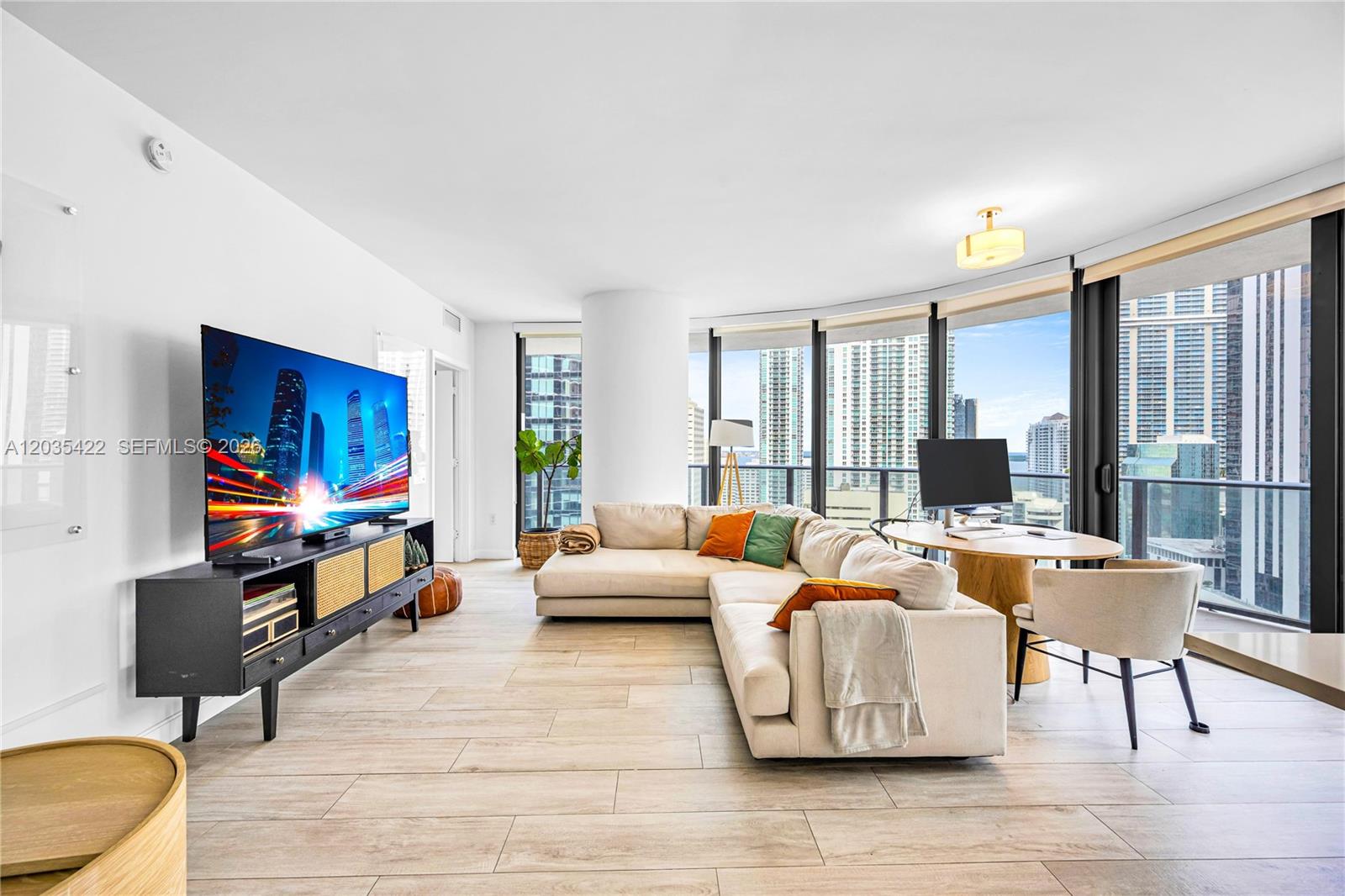 A modern living room features a sectional sofa, television console, and floor-to-ceiling windows with city views — 45 SW 9th St # 2103, Miami FL 33130, MIAMI, FL
