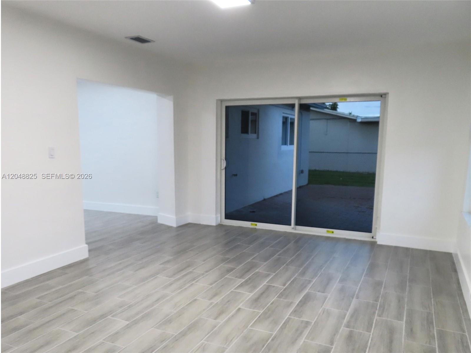 An interior room features light wood-look tile flooring, white walls, and a sliding glass door — 1030 SW 96th Ave # 1030, Miami FL 33174, MIAMI, FL