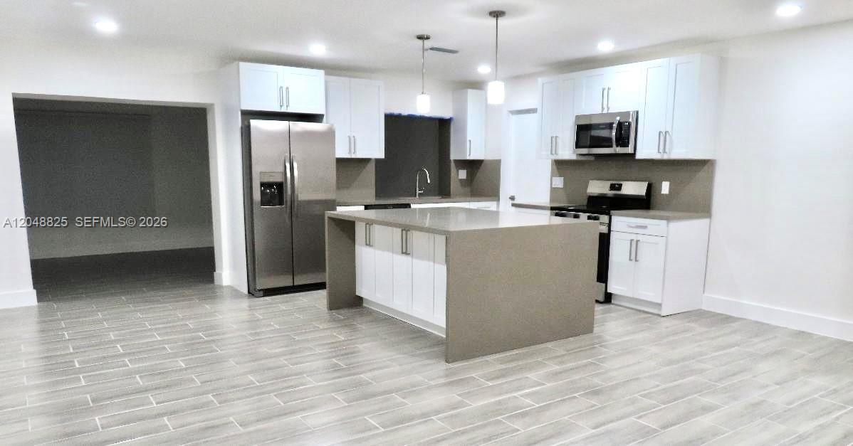A modern kitchen features white cabinets, stainless steel appliances, and a large gray island — 1030 SW 96th Ave # 1030, Miami FL 33174, MIAMI, FL
