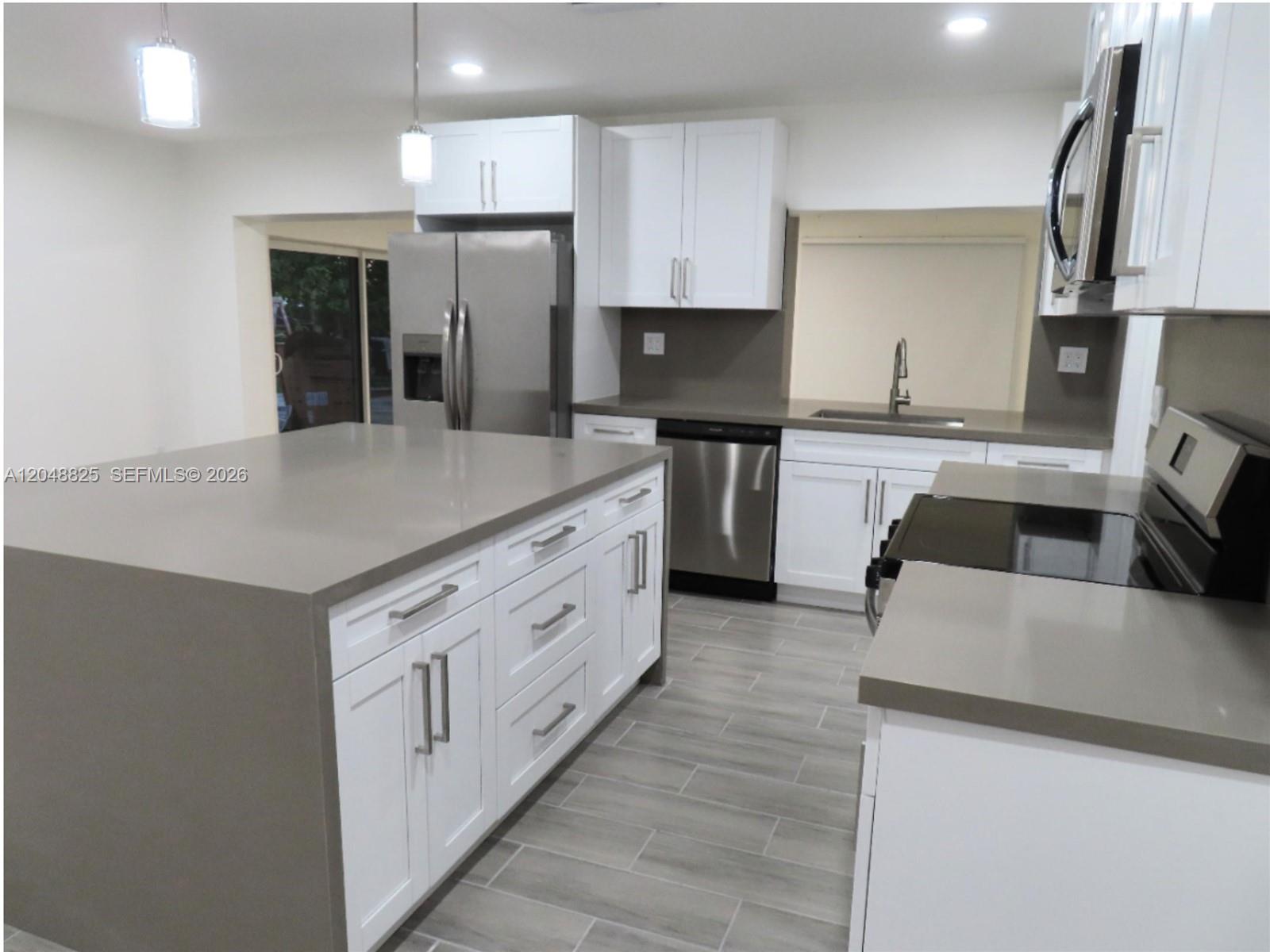 A modern kitchen features white cabinets, gray quartz countertops, stainless steel appliances, and tile flooring — 1030 SW 96th Ave # 1030, Miami FL 33174, MIAMI, FL