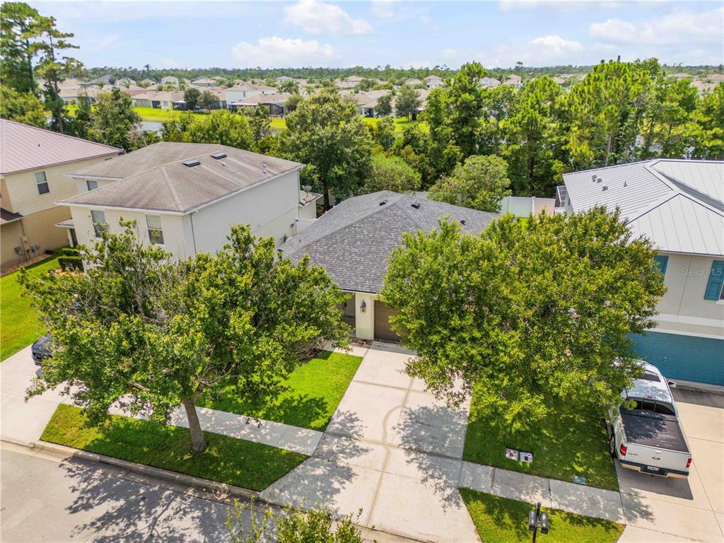 An elevated view of a suburban house with a driveway, lawn, and surrounding trees — 550 AEOLIAN DRIVE, NEW SMYRNA BEACH, FL