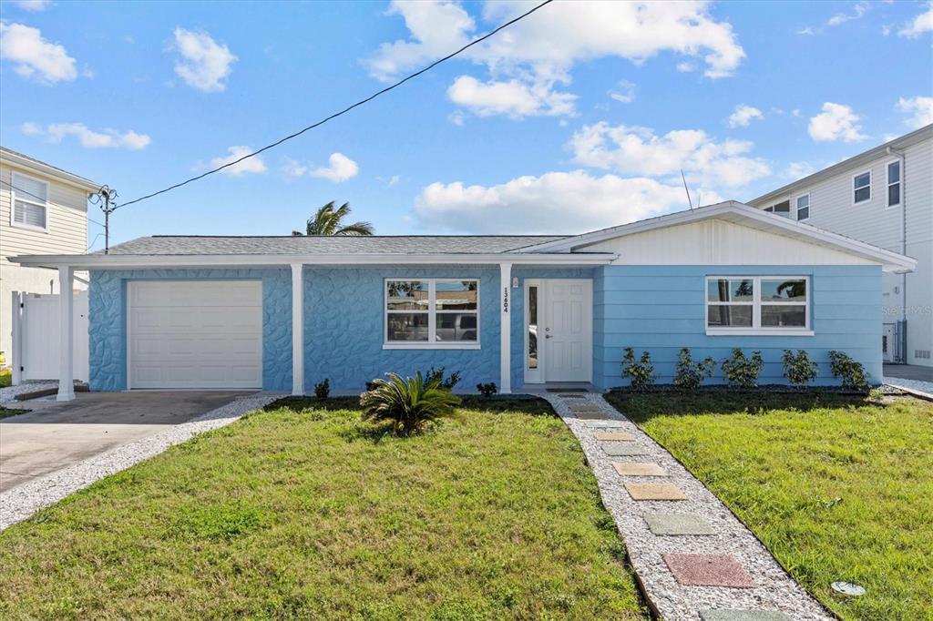 A single-story blue house with a white garage door and a stone walkway — 13604 MARIA DRIVE, HUDSON, FL