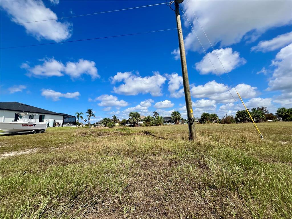 A vacant grassy lot features a utility pole and a boat parked nearby — 4109 NW 36TH TERRACE, CAPE CORAL, FL