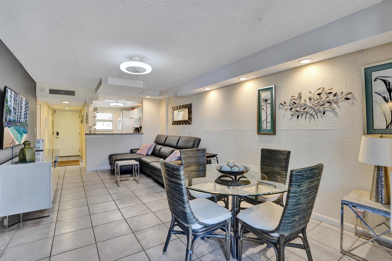 A living and dining area with tile floors, a glass table, and a leather sofa — 1391 S Ocean Boulevard, Pompano Beach FL 33062, POMPANO BEACH, FL