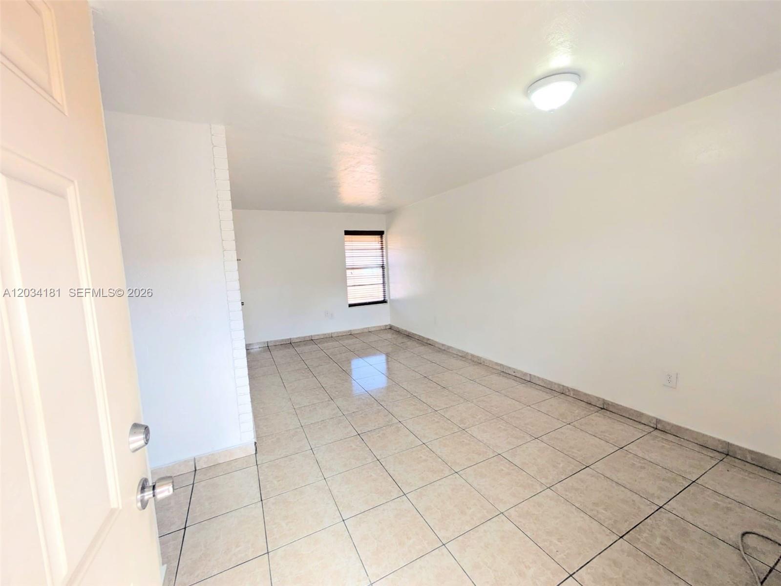 An empty room features white walls, light-colored tile flooring, and a single window with blinds — 6850 W 14th Ct # A28, Hialeah FL 33014, HIALEAH, FL