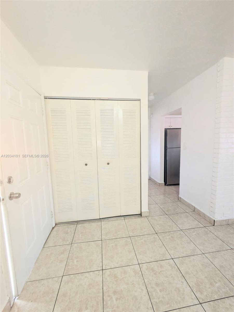 A tiled entryway features a white louvered closet door and a view into a kitchen — 6850 W 14th Ct # A28, Hialeah FL 33014, HIALEAH, FL