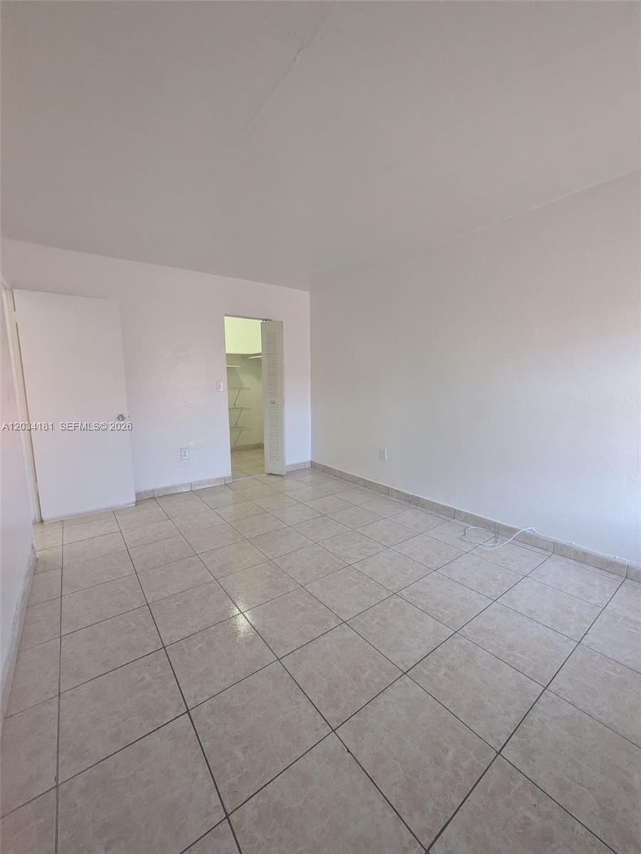 An empty room features white walls, light-colored tile flooring, and an open closet door — 6850 W 14th Ct # A28, Hialeah FL 33014, HIALEAH, FL