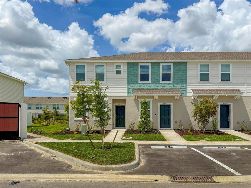 A row of three two-story townhomes with dark doors and a teal accent wall — 8948 DAYBREAK STREET, SARASOTA, FL