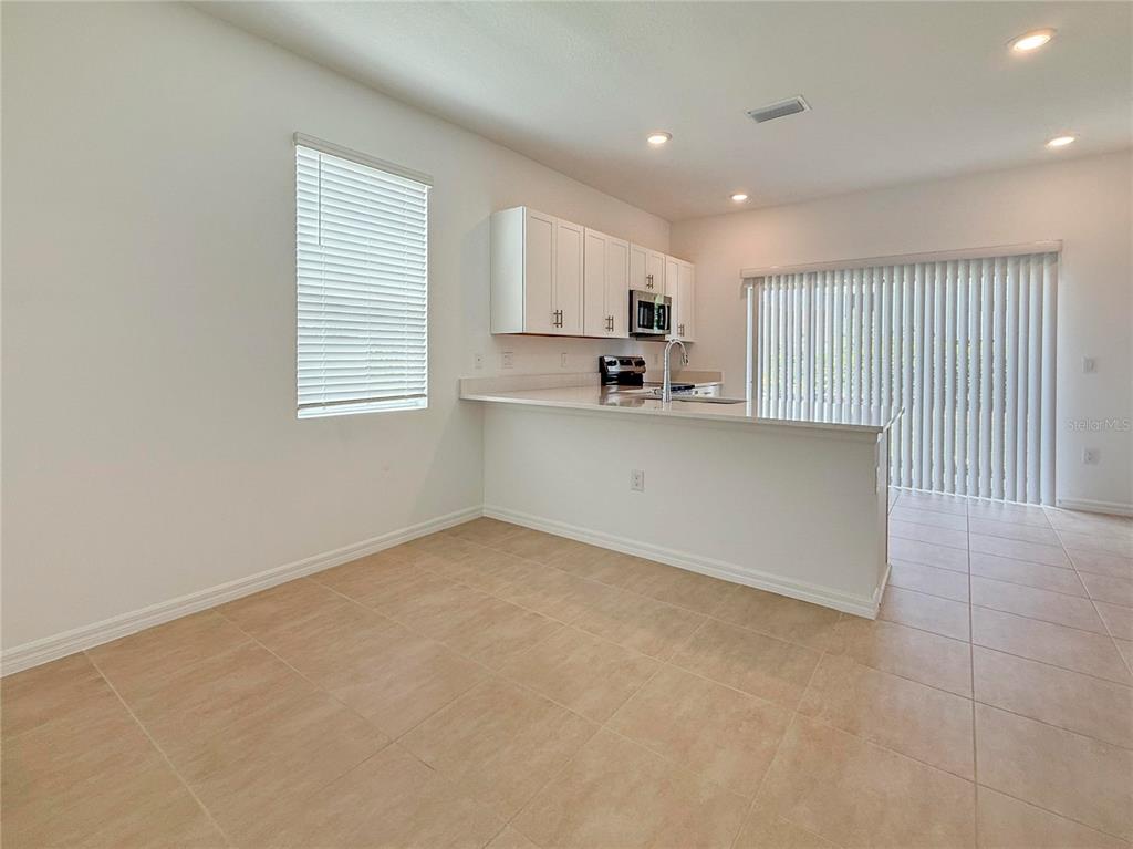 A kitchen with white cabinets and a breakfast bar overlooks an open dining area — 8948 DAYBREAK STREET, SARASOTA, FL