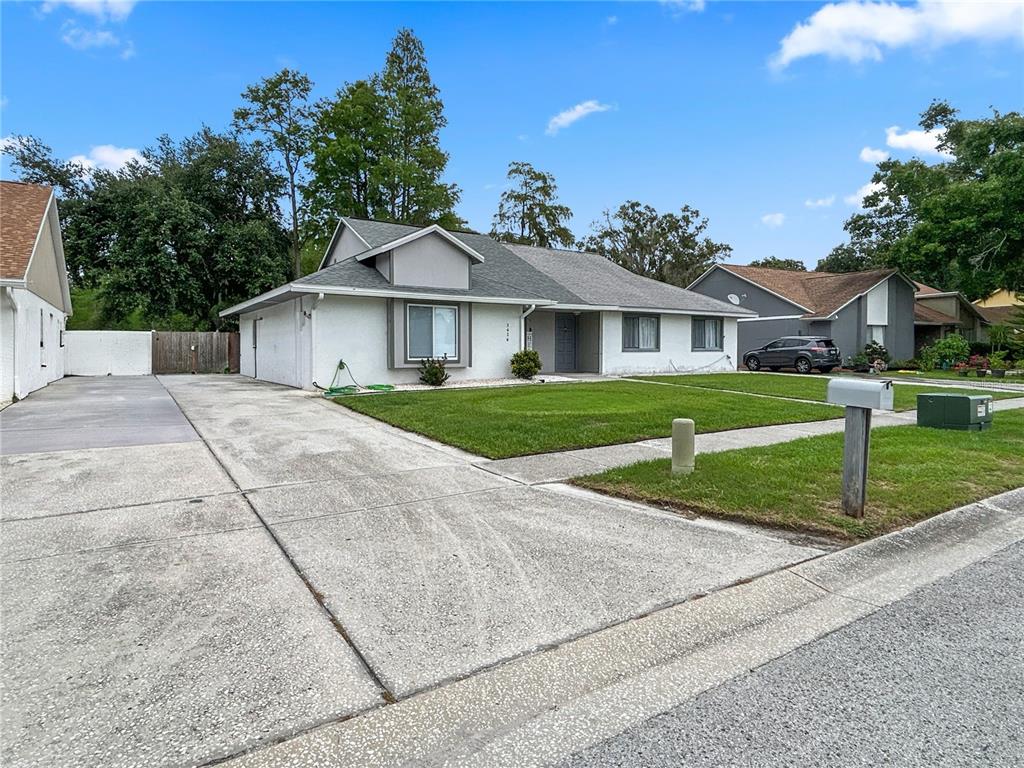 A single-story white house with a gray roof and a concrete driveway sits on grass — 3426 LAUREL DALE DRIVE, TAMPA, FL