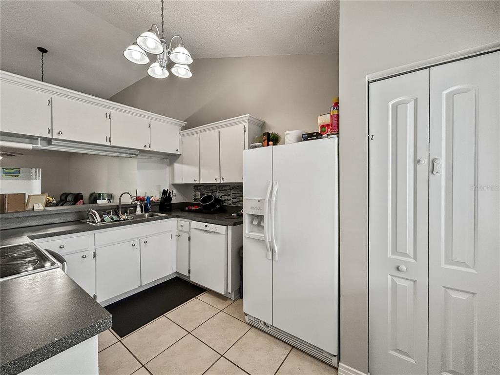 A kitchen features white cabinets, dark countertops, a white refrigerator, and a tiled floor — 3426 LAUREL DALE DRIVE, TAMPA, FL