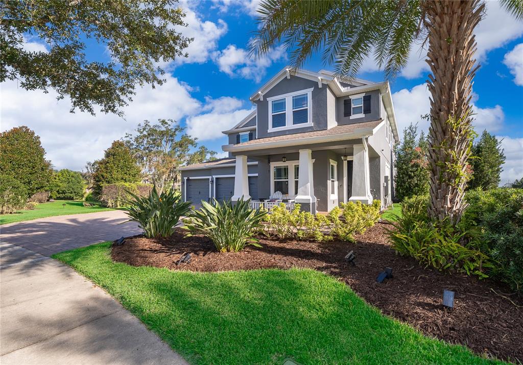 A two-story gray house with a front porch, garage, and landscaped yard under blue skies — 15838 CITRUS GROVE LOOP, WINTER GARDEN, FL