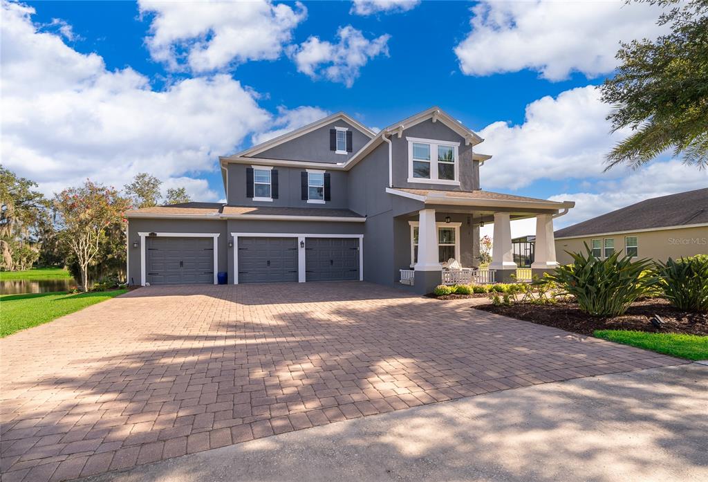 A two-story gray house features a three-car garage and a front porch with white columns — 15838 CITRUS GROVE LOOP, WINTER GARDEN, FL