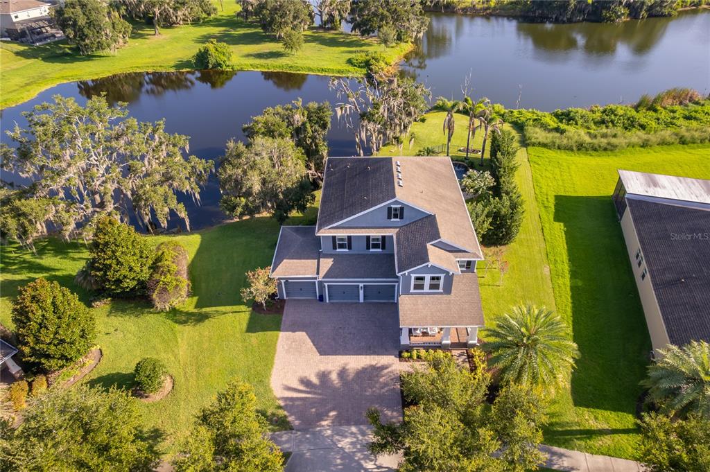 An aerial view shows a two-story house with a solar-paneled roof near a lake — 15838 CITRUS GROVE LOOP, WINTER GARDEN, FL