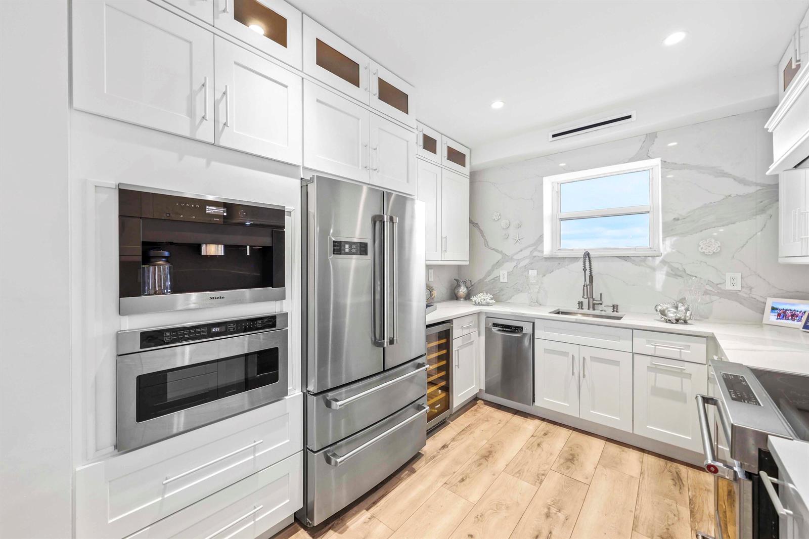 A modern kitchen features white cabinetry, stainless steel appliances, and a marble backsplash — 2921 S Ocean Boulevard # 704, Highland Beach FL 33487, HIGHLAND BEACH, FL