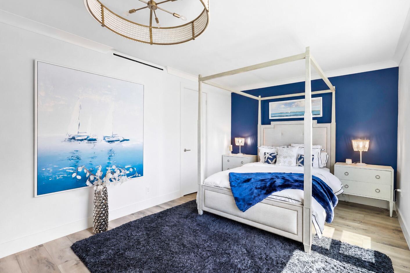 A bedroom features a canopy bed, a blue accent wall, and a large sailboat painting — 2921 S Ocean Boulevard # 704, Highland Beach FL 33487, HIGHLAND BEACH, FL