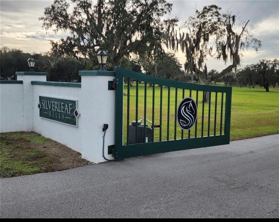A green metal gate with a circular logo stands at the entrance to Silverleaf Hills — 16070 SE 55 AVE RD, SUMMERFIELD, FL