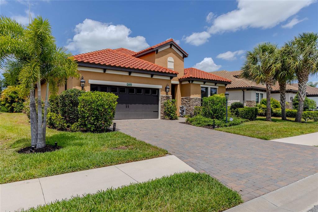 A single-story house with a tile roof, stone accents, and a paved driveway — 26858 WEISKOPF DRIVE, ENGLEWOOD, FL