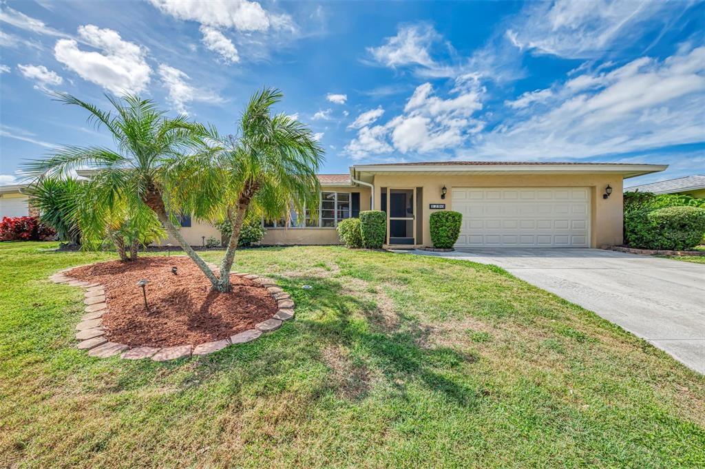 A single-story house with a beige exterior, a two-car garage, and a palm tree — 1290 LAKESIDE DRIVE, VENICE, FL