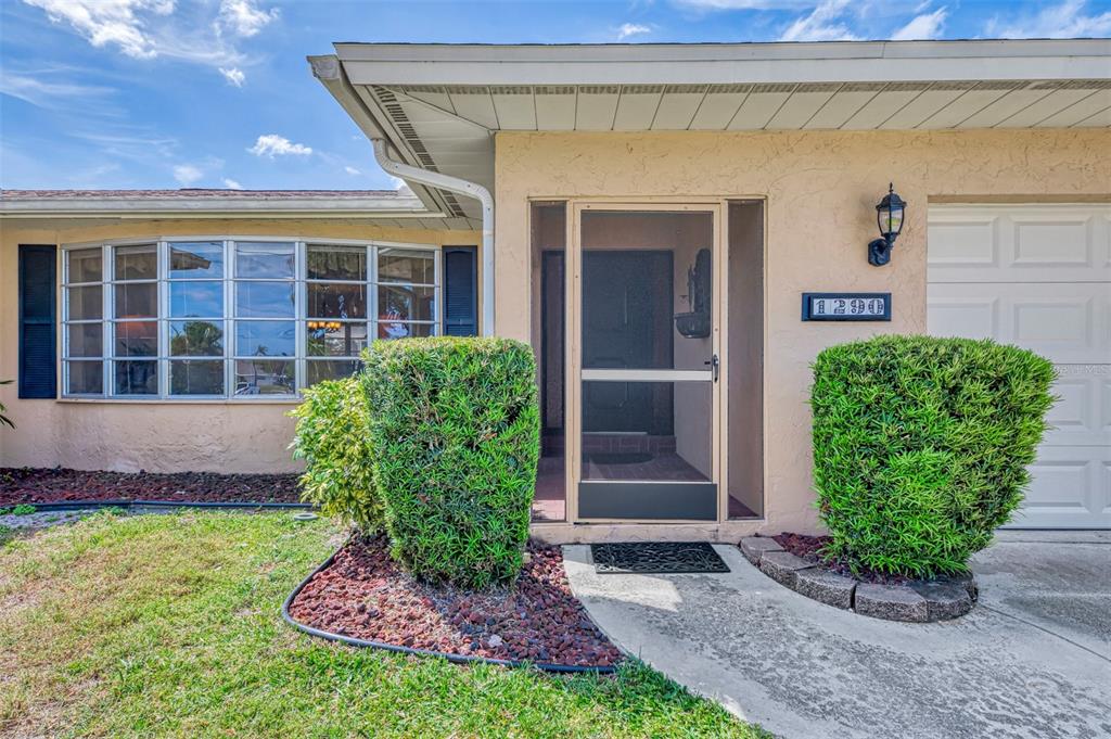 The exterior of a house features a screened front entryway, a bay window, and landscaping — 1290 LAKESIDE DRIVE, VENICE, FL