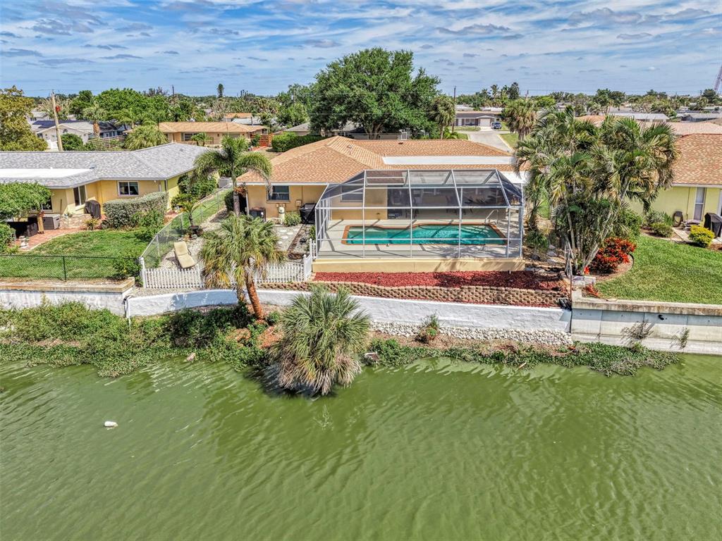 An aerial view of a waterfront house with a screened-in pool and a seawall — 1290 LAKESIDE DRIVE, VENICE, FL