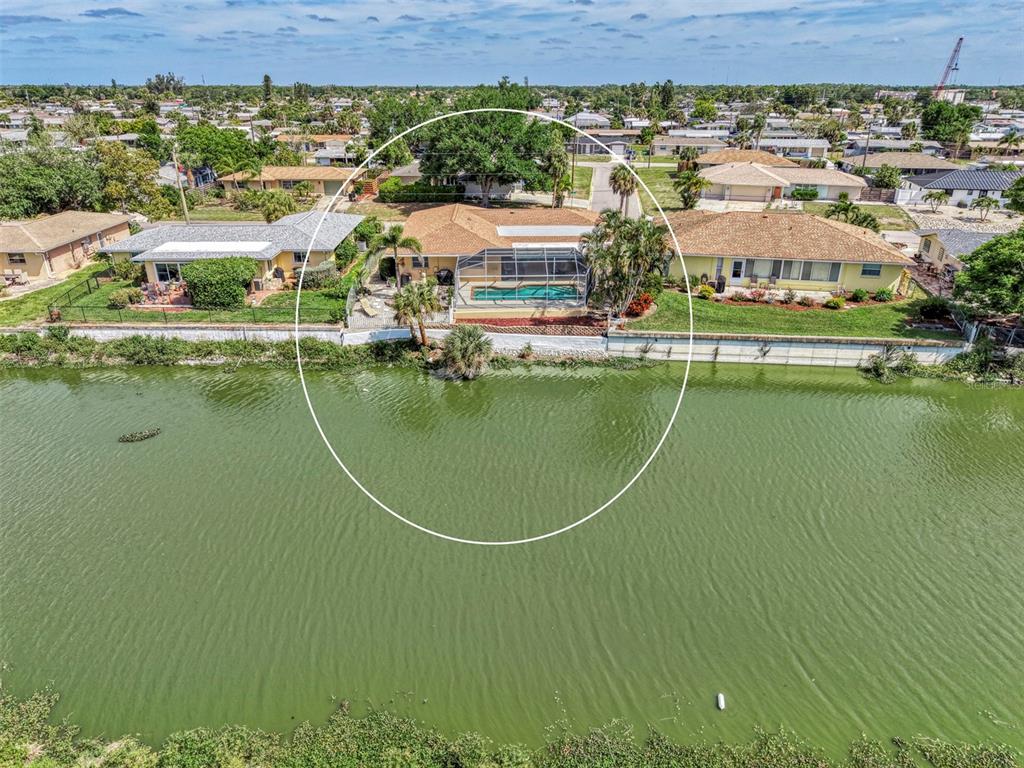 An aerial view shows a waterfront house with a screened-in pool and a tan roof — 1290 LAKESIDE DRIVE, VENICE, FL