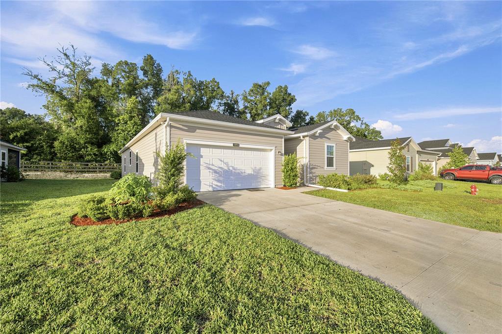 A single-story house with beige siding, a two-car garage, and a concrete driveway — 3492 NE 38TH LANE, OCALA, FL