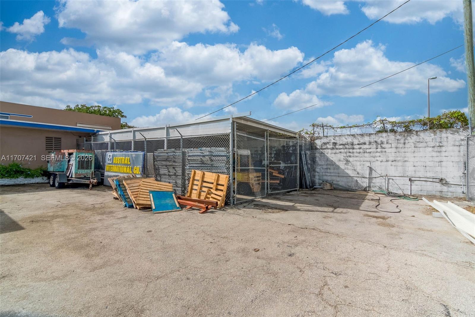 An outdoor storage area features a chain-link enclosure, wooden pallets, and a concrete wall — 3200 NW South River Dr, Miami FL 33142, MIAMI, FL