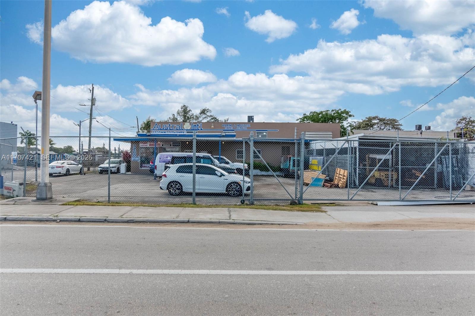 A fenced-in commercial property features a single-story building with a parking lot and vehicles — 3200 NW South River Dr, Miami FL 33142, MIAMI, FL