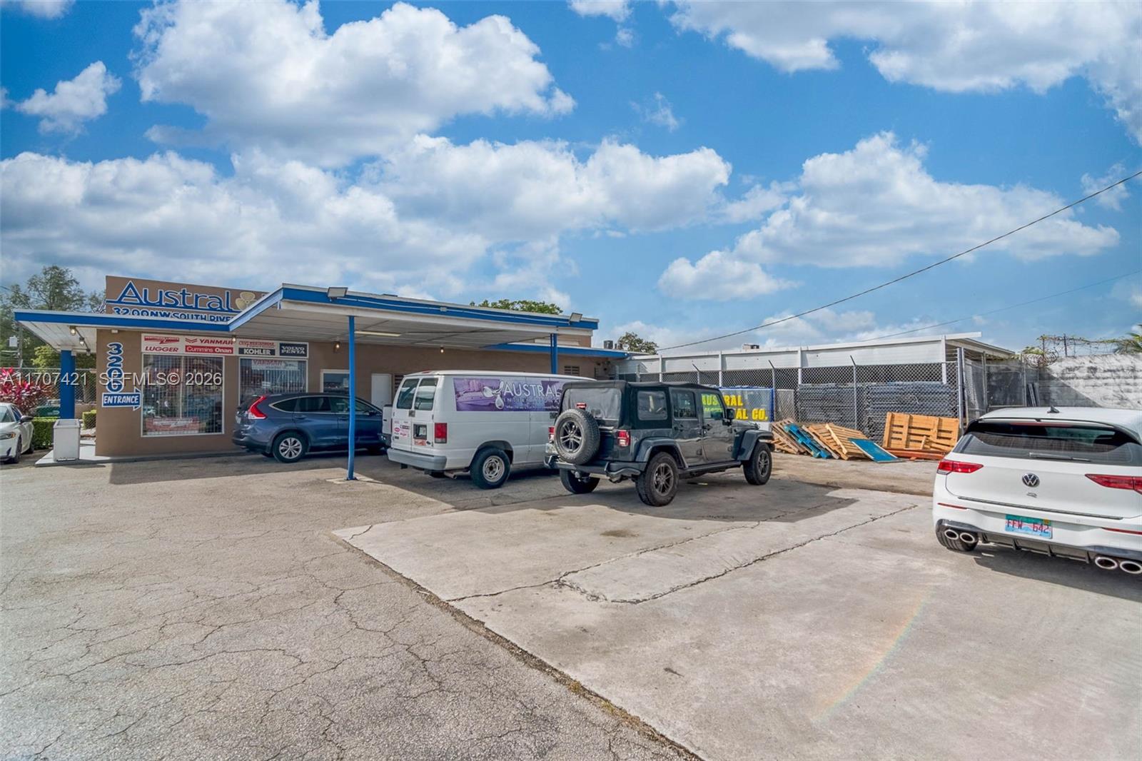 An exterior view of a commercial building with a parking lot and several parked vehicles — 3200 NW South River Dr, Miami FL 33142, MIAMI, FL