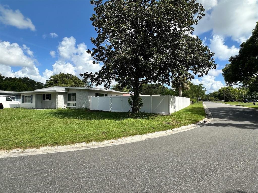 A single-story house with a white fence and a large tree in the front yard — 156 PINECREST DR, SANFORD, FL