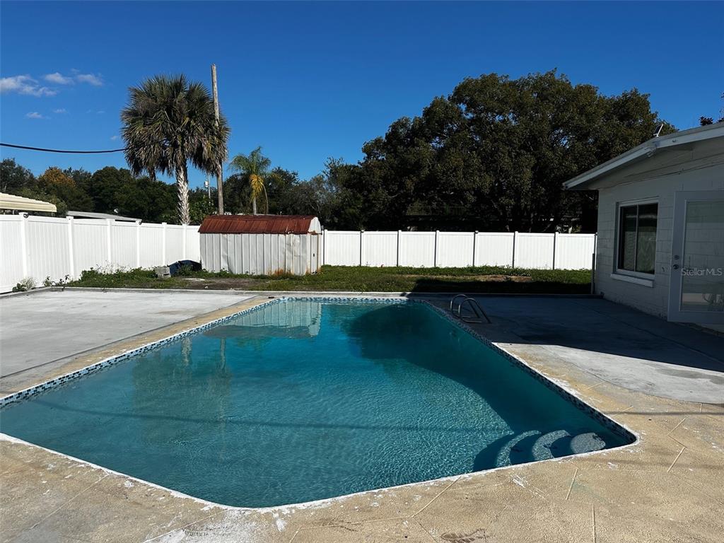 A backyard features a rectangular swimming pool, a white vinyl fence, and a storage shed — 156 PINECREST DR, SANFORD, FL