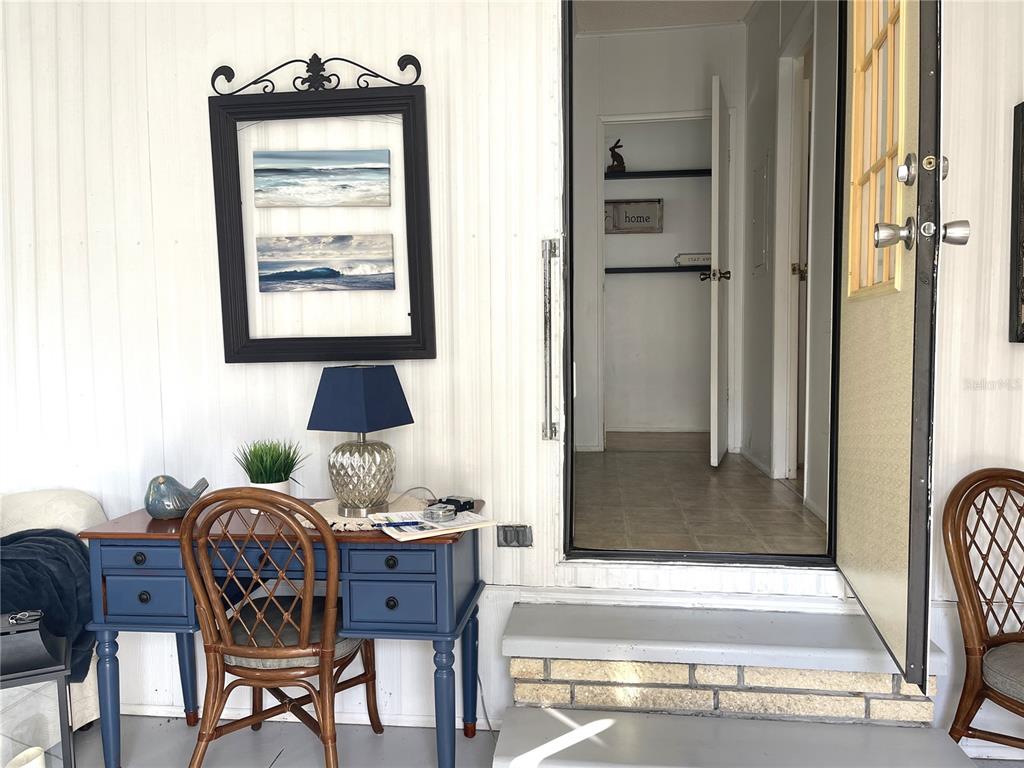 A blue desk and chair sit on a porch next to an open doorway — 312 S TIMBER TRL, WILDWOOD, FL