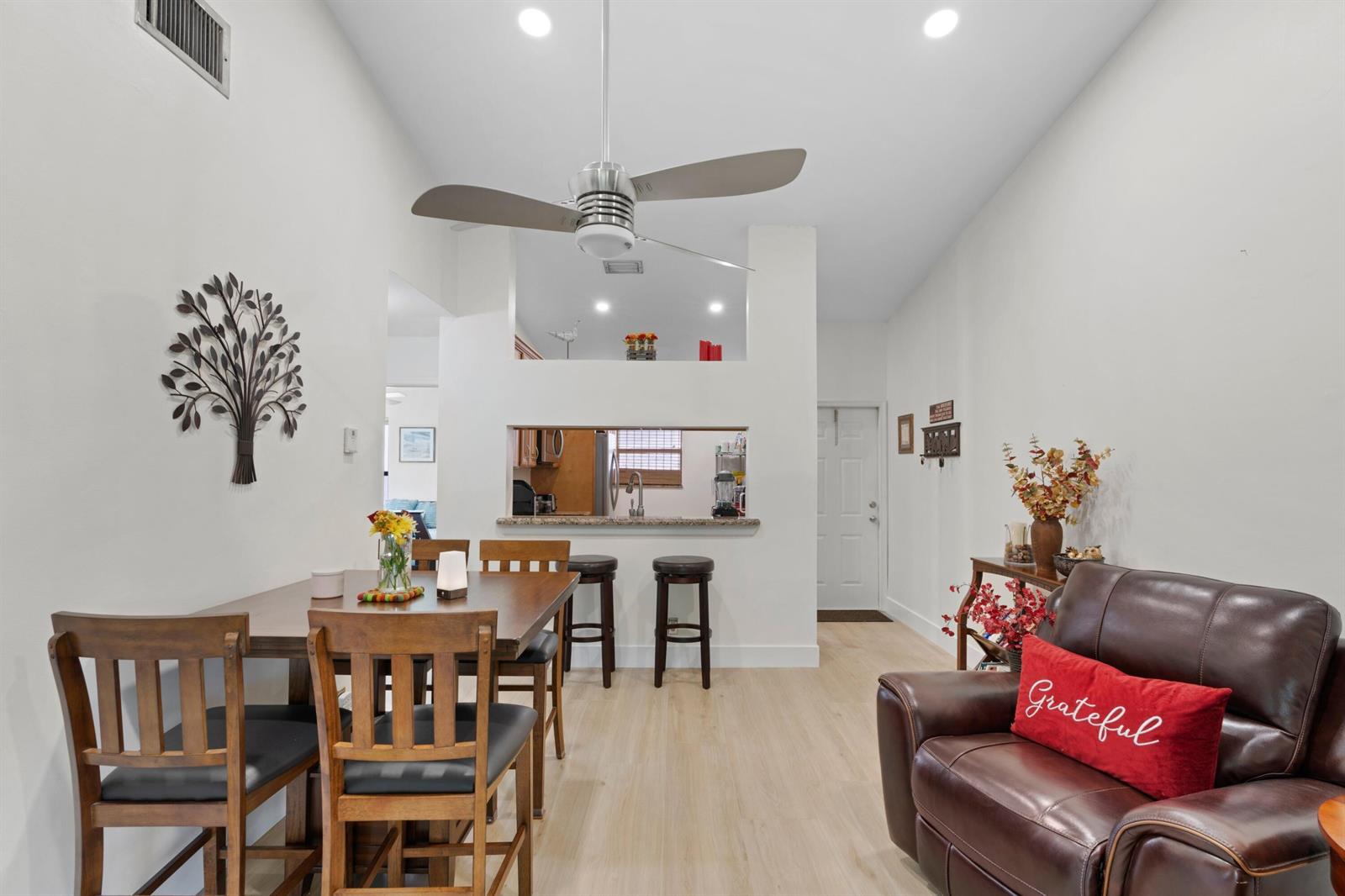 A dining area and living space feature a kitchen pass-through, ceiling fan, and wood flooring — 3355 Jaywood Terrace # 2110, Boca Raton FL 33431, BOCA RATON, FL