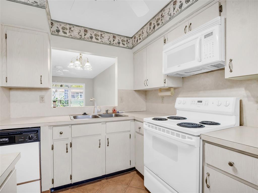 A bedroom features a bed with a beige headboard, a ceiling fan, and an attached bathroom — 3109 MISSION GROVE DRIVE UNIT D, PALM HARBOR, FL