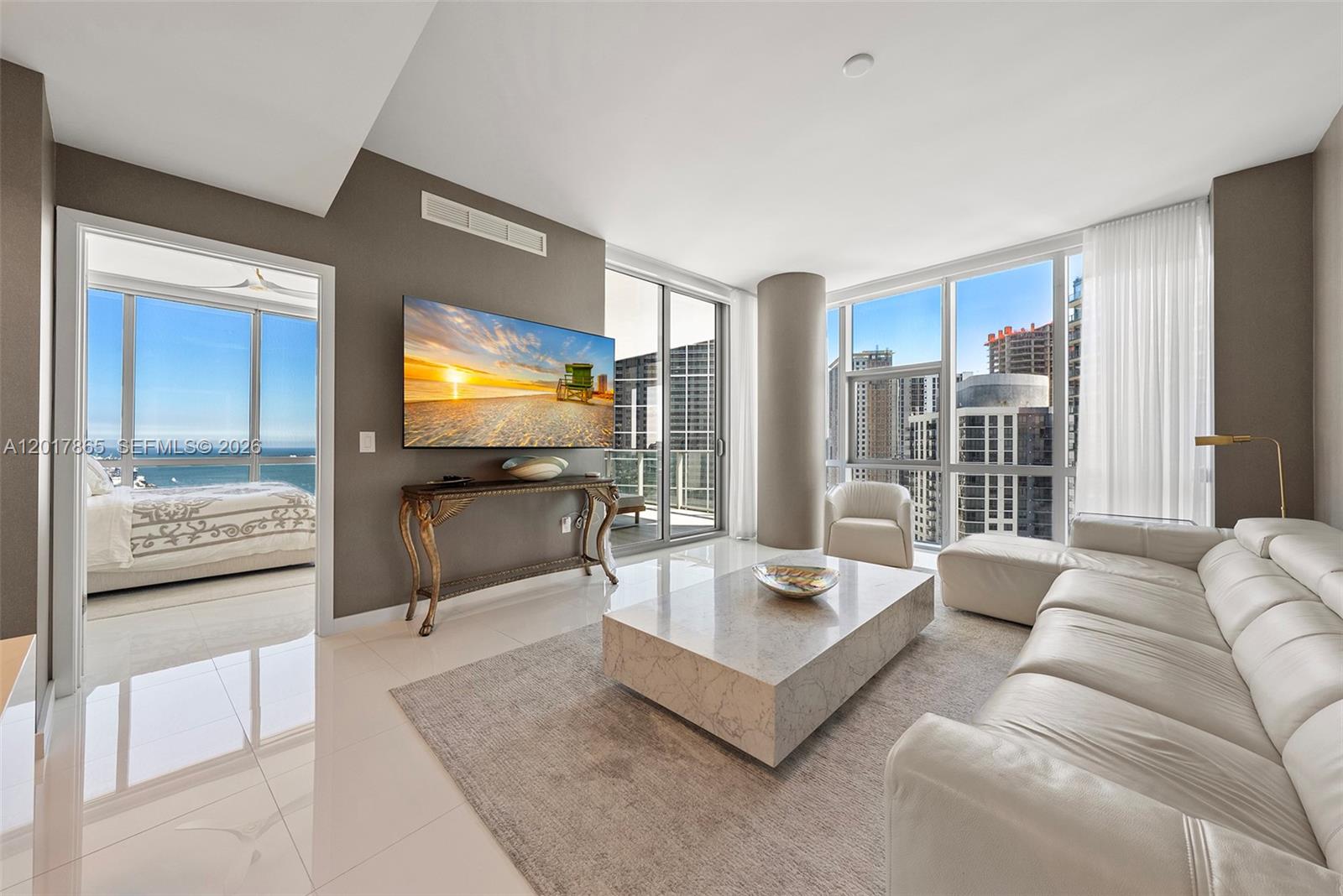 A modern living room features a white leather sofa, marble coffee table, and city views — 851 NE 1st Ave # 3711, Miami FL 33132, MIAMI, FL