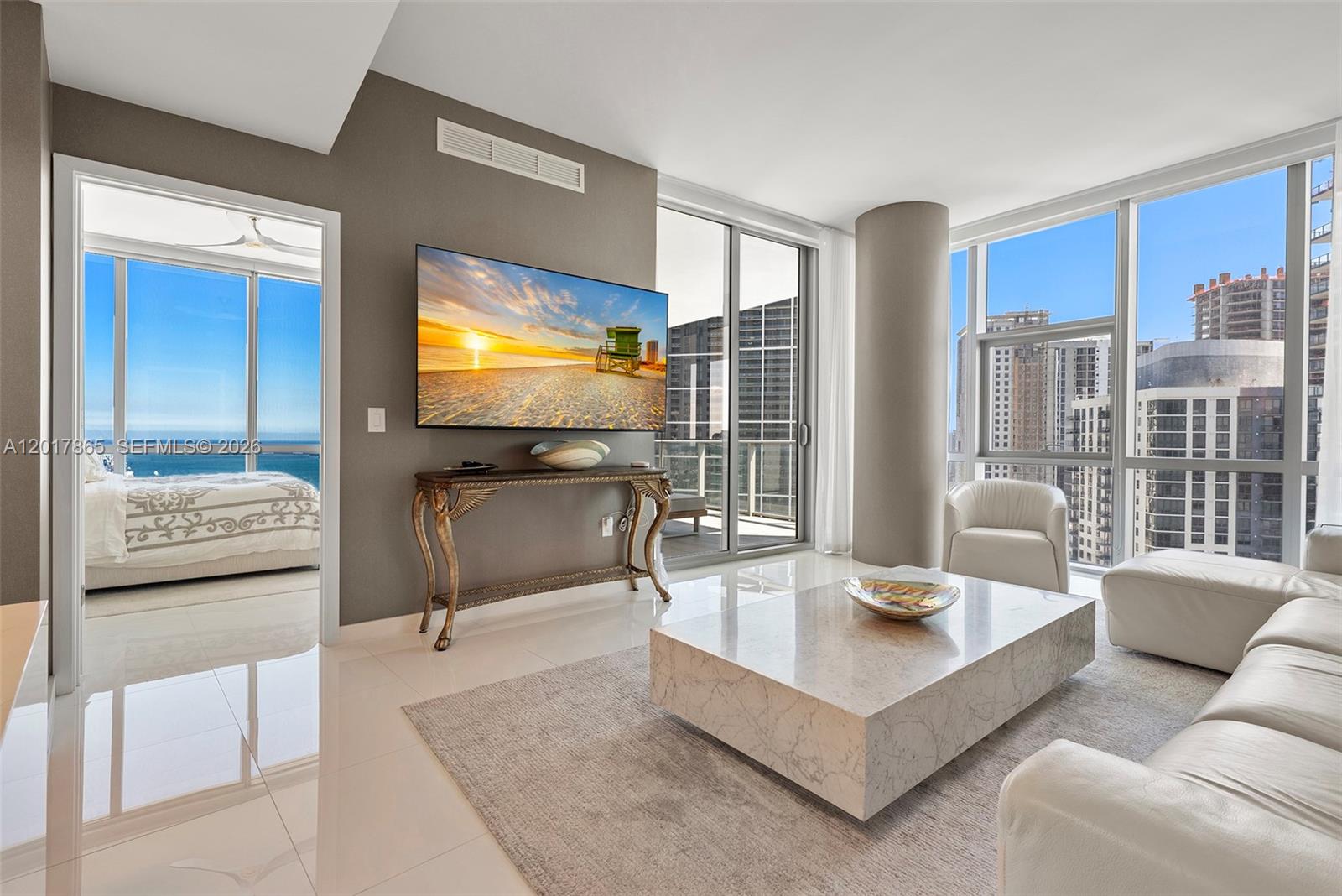 A modern living room features a marble coffee table, wall-mounted television, and floor-to-ceiling windows — 851 NE 1st Ave # 3711, Miami FL 33132, MIAMI, FL