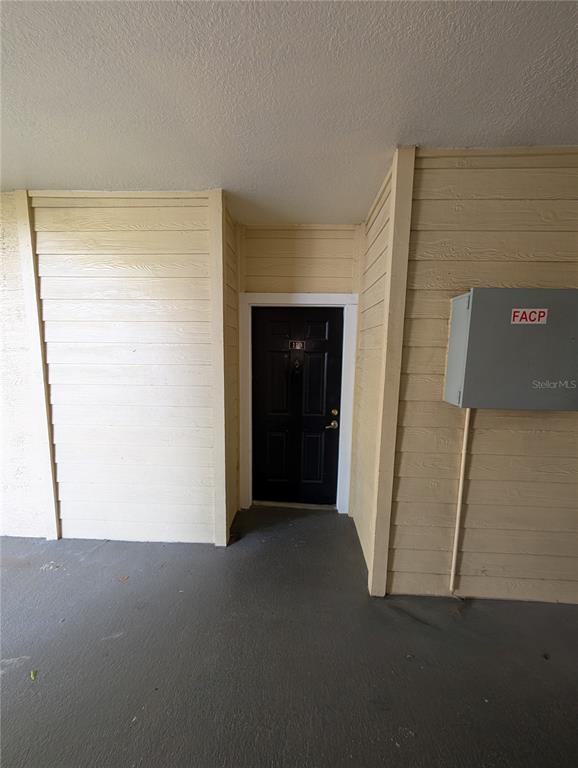 A black front door is set into a beige, wood-sided exterior wall with a utility box — 2632 ROBERT TRENT JONES DRIVE UNIT 110, ORLANDO, FL