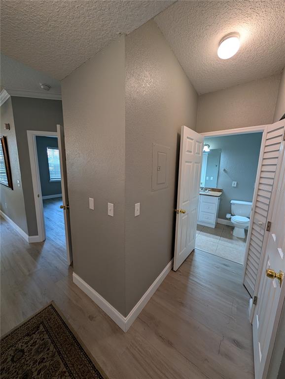 A hallway with light wood-look flooring leads to a bathroom and a bedroom — 2632 ROBERT TRENT JONES DRIVE UNIT 110, ORLANDO, FL