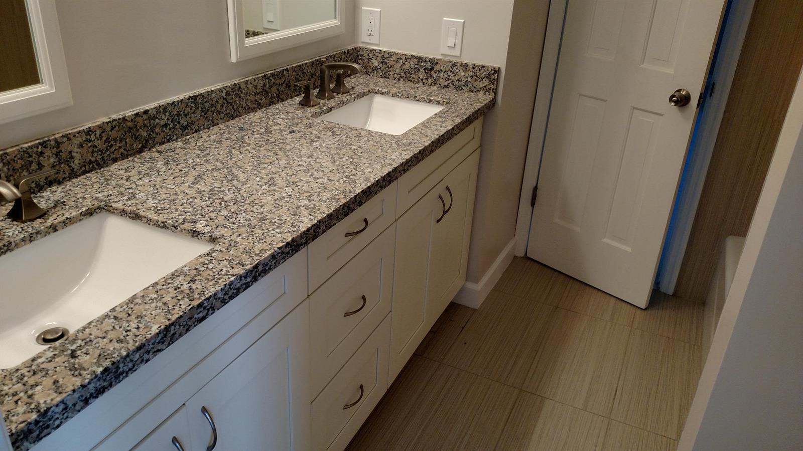 A bathroom vanity features a granite countertop, dual white sinks, and white cabinetry — 451 W Conference Drive, Boca Raton FL 33486, BOCA RATON, FL