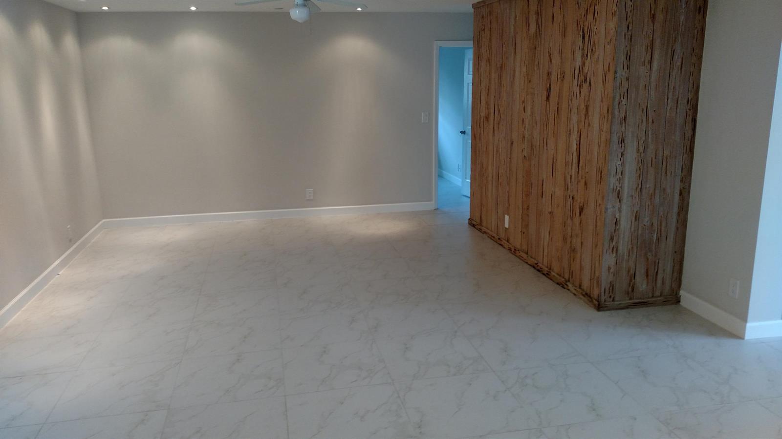 An empty room features light gray walls, white marble-look tile flooring, and a wood-paneled wall — 451 W Conference Drive, Boca Raton FL 33486, BOCA RATON, FL