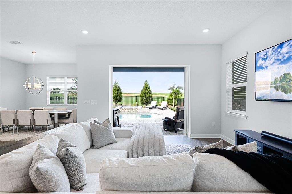 A living room with a sectional sofa opens to a patio with a swimming pool — 15734 VETTA DRIVE, MONTVERDE, FL