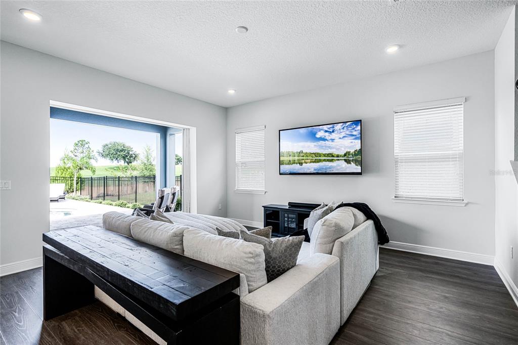 A living room features a sectional sofa, a console table, and a wall-mounted television — 15734 VETTA DRIVE, MONTVERDE, FL