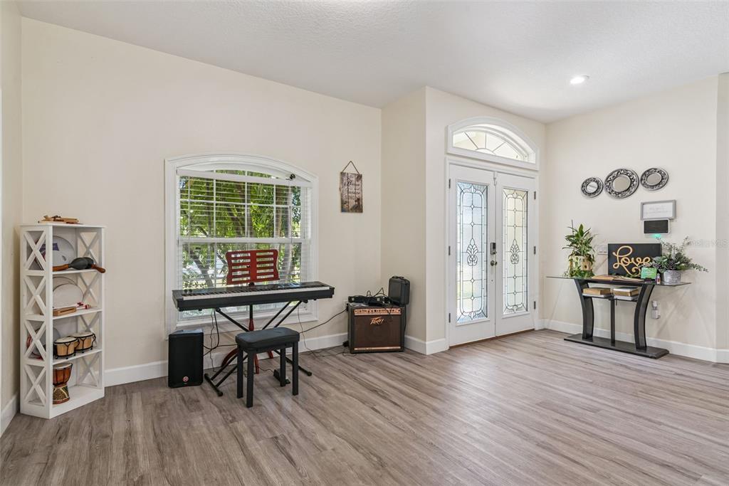 A bright room with wood-look flooring, a keyboard, and a glass-topped console table near the entrance — 5211 SW 103RD LOOP, OCALA, FL