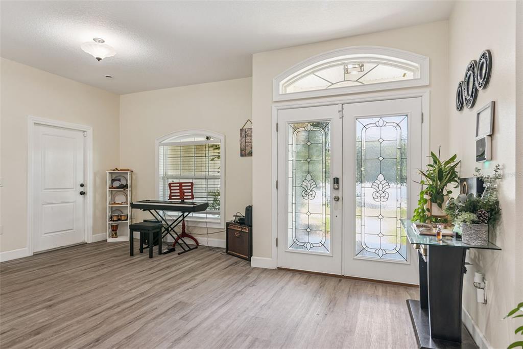 A bright entryway features light wood-look flooring, double glass-paneled front doors, and a keyboard station — 5211 SW 103RD LOOP, OCALA, FL
