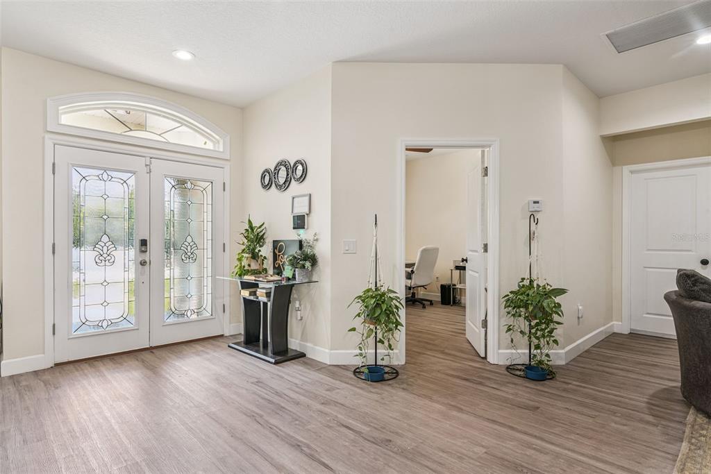 An entryway with wood-look flooring, a glass-paneled double front door, and an adjacent home office — 5211 SW 103RD LOOP, OCALA, FL